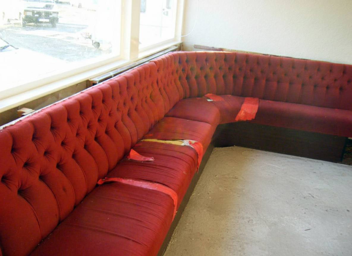 Worn red tufted club bench seating before restoration