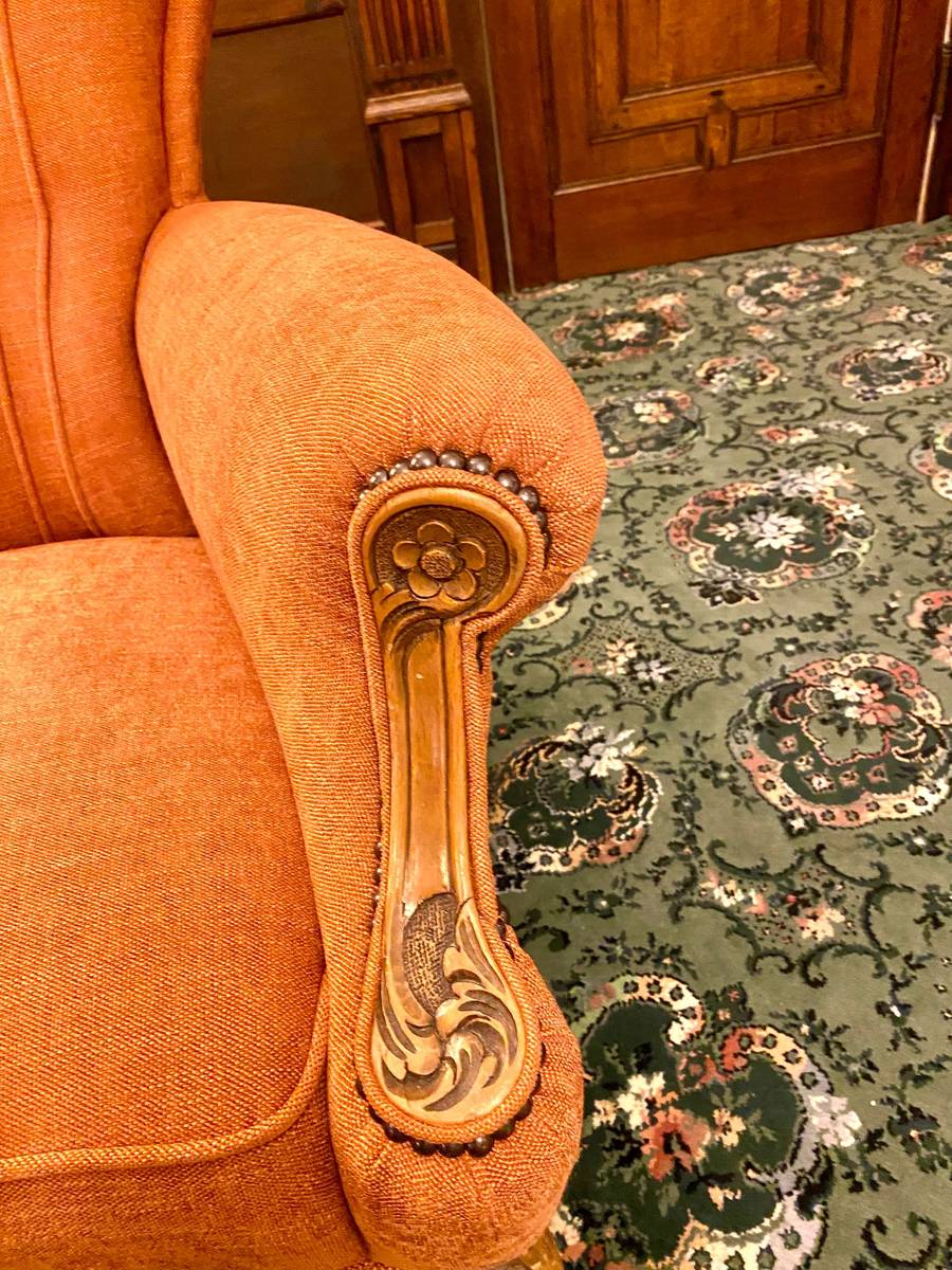 Close-up of carved gilt arm detail with nailhead studding