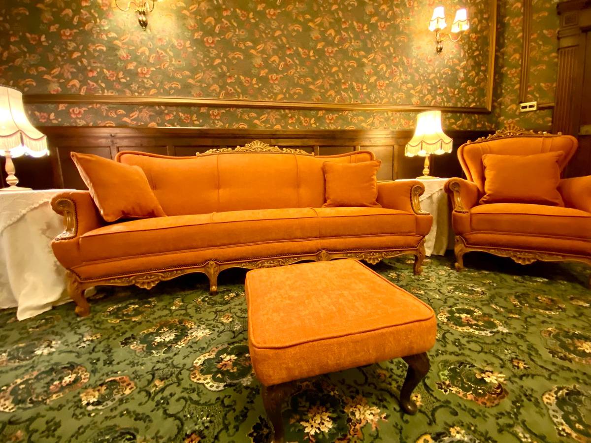 French rococo suite in period room with dark oak panelling, floral wallpaper and twin wall lamps