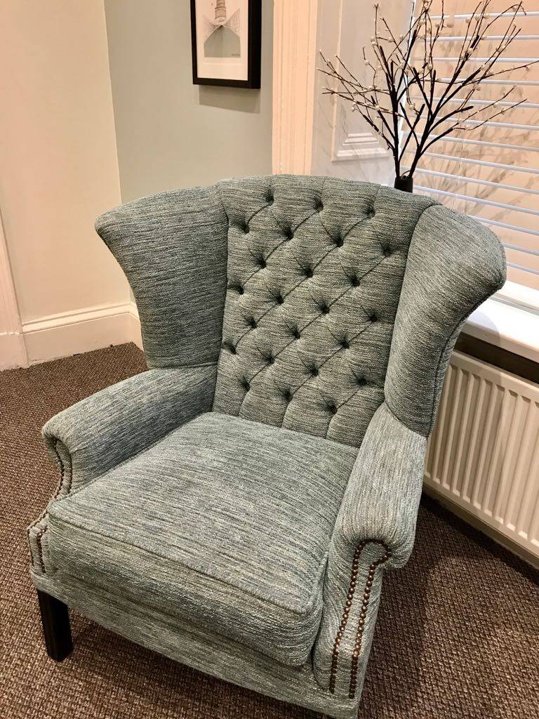 Button-tufted wingback armchair in teal fabric with nailhead trim
