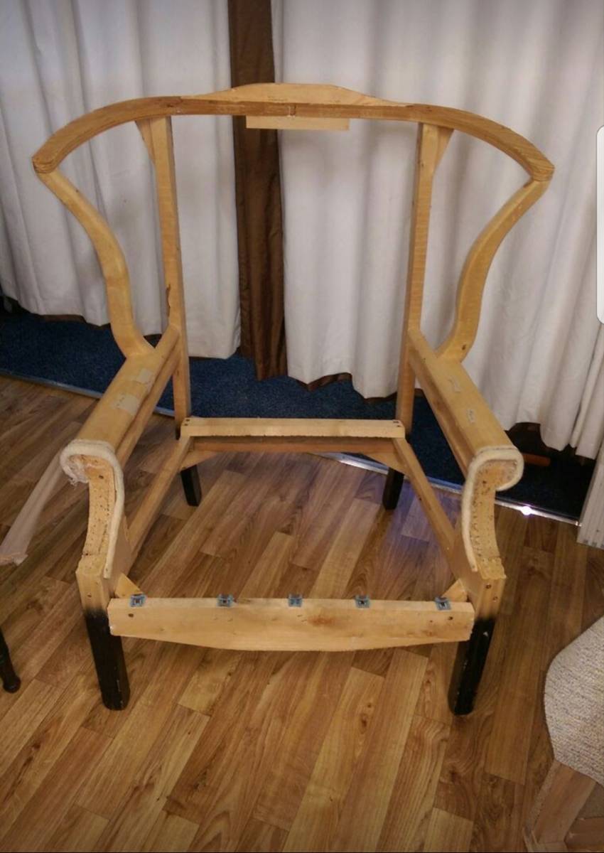 Wingback chair stripped to bare wooden frame in workshop
