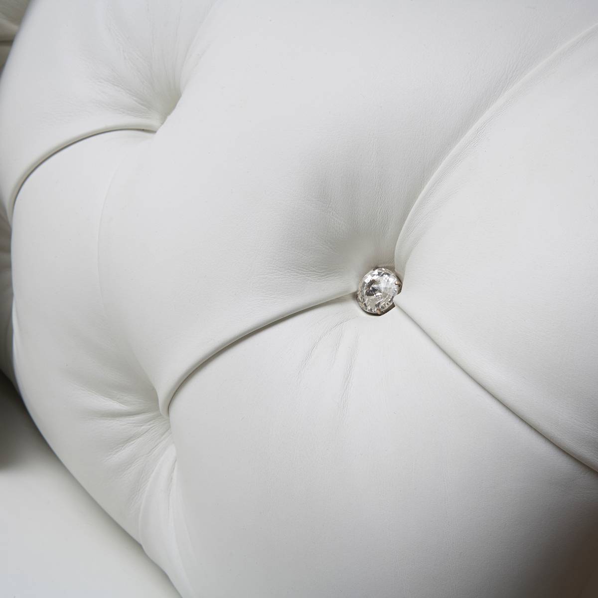 Crystal button tufting close-up on white leather